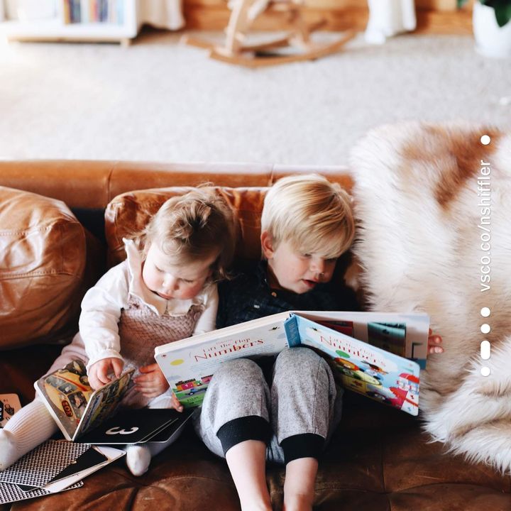 Two kids reading together on a leather couch