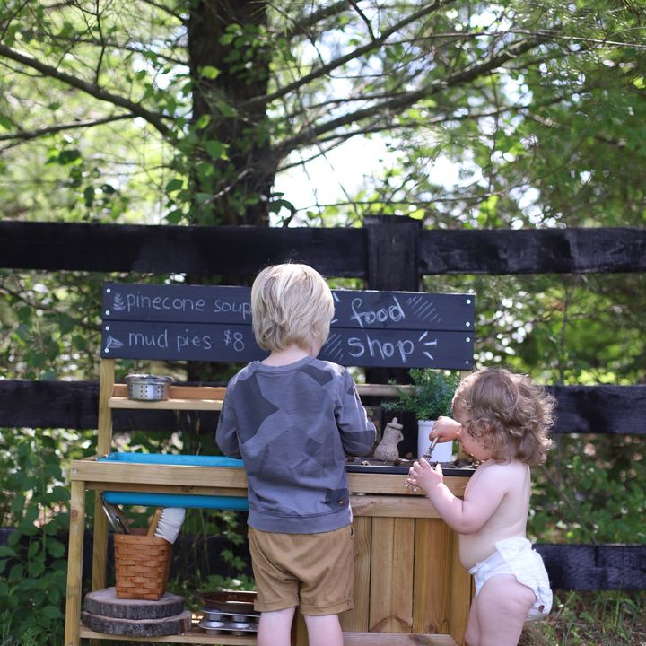 Two kids cooking in an outdoor mud kitchen