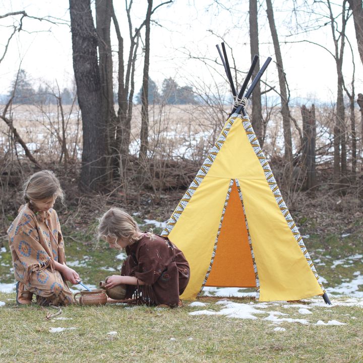 Kids playing by a yellow teepee in the yard